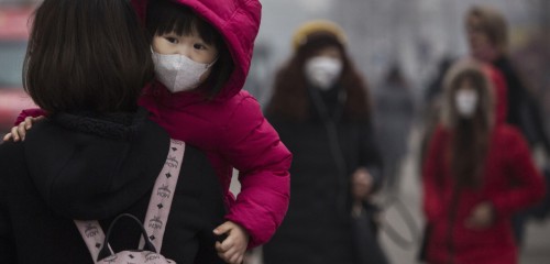 BEIJING, CHINA - DECEMBER 08: A Chinese girl wears a mask to protect against pollution as she is carried in a shopping district in heavy smog on December 8, 2015 in Beijing, China. The Beijing government issued a "red alert" for the first time since new standards were introduced earlier this year as the city and many parts of northern China were shrouded in heavy pollution. Levels of PM 2.5, considered the most hazardous, crossed 400 units in Beijing, lower than last week, but still nearly 20 times the acceptable standard set by the World Health Organization. The governments of more than 190 countries are meeting in Paris to set targets on reducing carbon emissions in an attempt to forge a new global agreement on climate change. (Photo by Kevin Frayer/Getty Images)